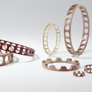 Podem-se observar vários componentes em forma de anel, em diferentes tamanhos e cores, com recortes redondos distribuídos uniformemente ou bordas texturizadas.