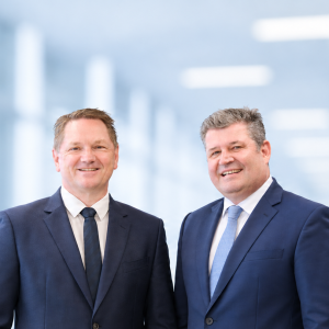 The managing directors of Krempel GmbH are standing against a light-colored background and smiling at the camera.