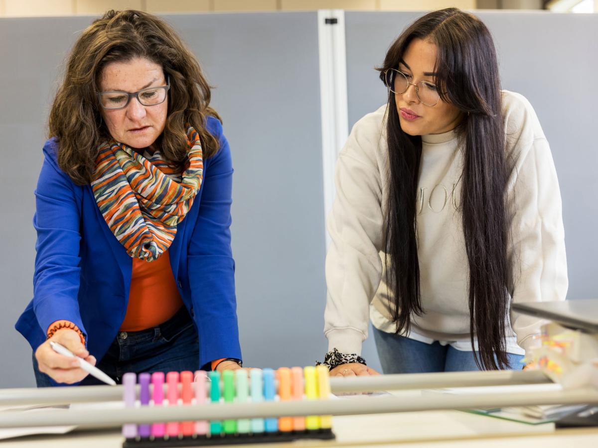 Two women standing at a table and lookint at a piece of paper