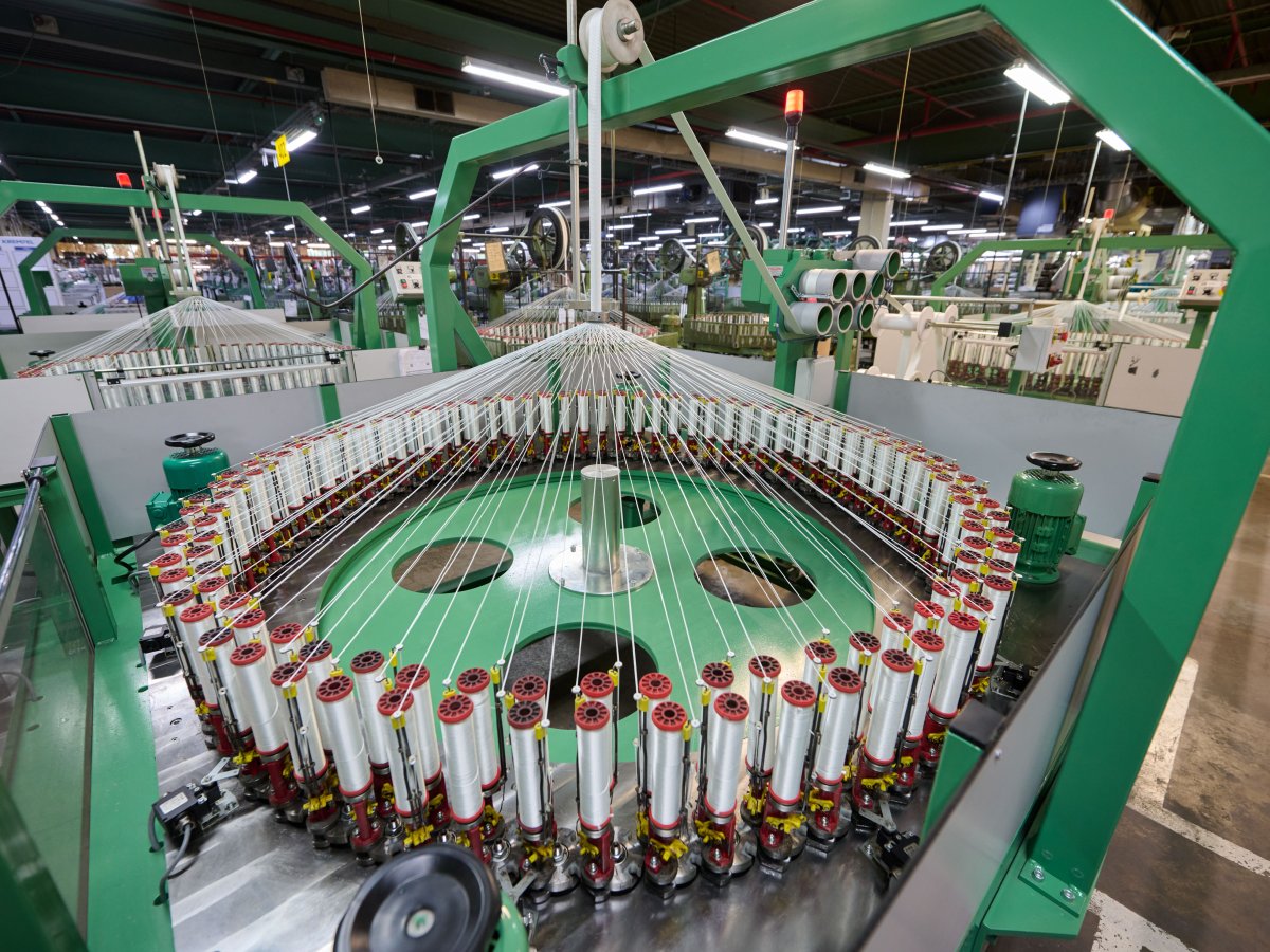A braiding machine in Lonridge in which numerous spools of yarn are arranged in a circle, and the threads run from there to the center of the machine to be braided